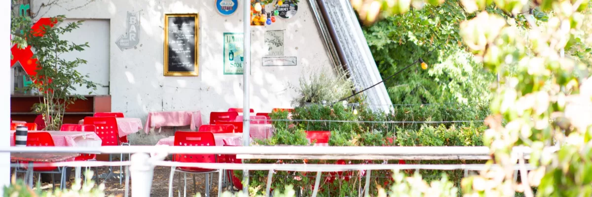 Rote St&uuml;hle und weiss gedeckte Tische im Garten