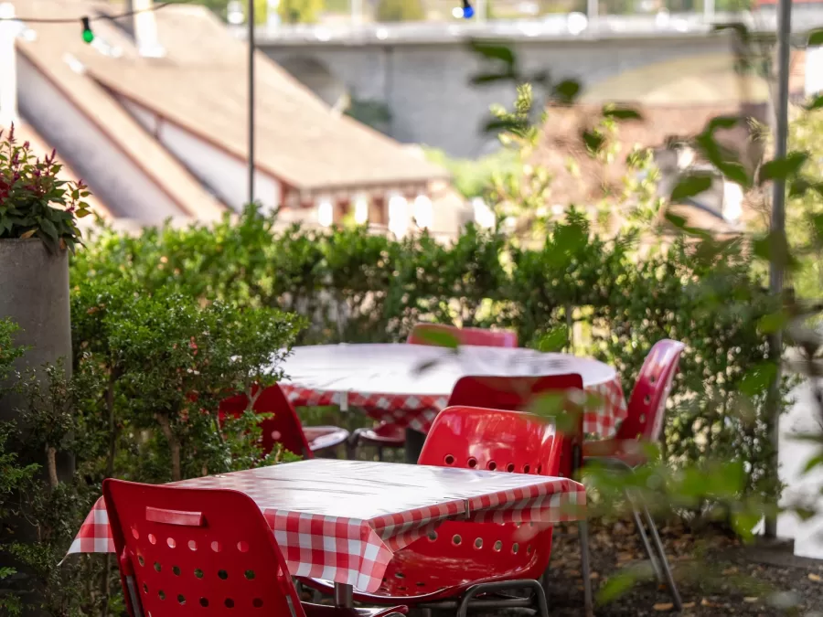 Rote St&uuml;hle und rotweiss karierte Tische auf der Gartenterrasse, dahinter die D&auml;cher der Badener Altstadt